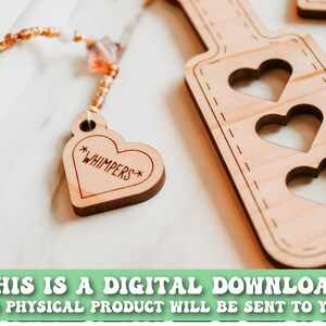 May include: Wooden paddle with three heart cutouts and a heart-shaped tag that says "*WHIMPERS*". The tag is attached to a beaded strand. The text at the bottom says "THIS IS A DIGITAL DOWNLOAD NO PHYSICAL PRODUCT WILL BE SENT TO YOU".