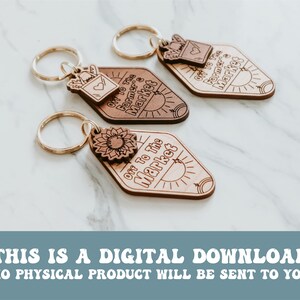 May include: Three wooden keychains with a diamond shape and a gold key ring. Each keychain has a different design. One has a sunflower, another has a small mailbox with a heart, and the third has a sun. All three keychains have the text "Off to the Market" on them.