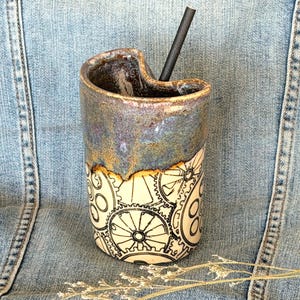 May include: A set of three ceramic mugs with a speckled, matte finish. The mugs are in cream, light grey, and dark grey. Each mug has a simple, minimalist design, ideal for coffee or tea.