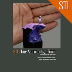 May include: A small, white astronaut figurine standing on a purple and black rock formation. The figurine is 15mm tall and is painted in a realistic style. The text "STL: Tiny Astronauts, 15mm" is visible below the figurine.