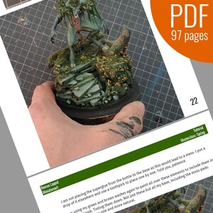 May include: A green and brown miniature figure of a creature with antlers and a toothy grin standing on a base of moss, rocks, and branches. The base is on a wooden round platform. The image is from a tutorial on miniature painting.