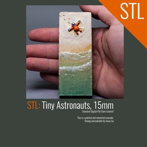May include: A miniature astronaut figure in an orange spacesuit with a white helmet is standing on a small, rectangular base with a painted beach scene. The base is made of a light brown material and has a green and blue painted ocean scene with white waves. The base is 15mm in size. The text "STL: Tiny Astronauts, 15mm" is printed below the base. The text "Standard Digital File Store License*" is printed below the text "STL: Tiny Astronauts, 15mm". The text "This is a painted and converted example." is printed below the text "Standard Digital File Store License*". The text "Basing and paintjob by Josua Lai." is printed below the text "This is a painted and converted example."
