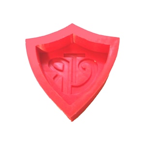 May include: Red silicone mold shaped like a shield with a raised design of a stylized letter "P" inside.