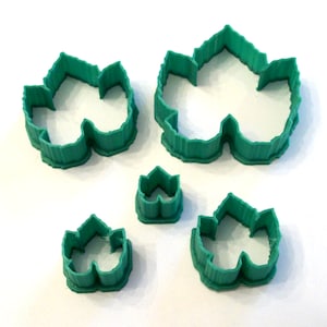 May include: Set of four green plastic leaf-shaped cookie cutters. The cutters are in different sizes.
