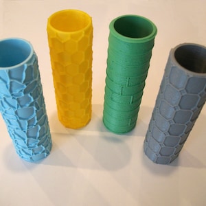 May include: Four different textured paint rollers. The rollers are made of a soft, flexible material and have a variety of patterns. The rollers are blue, yellow, green, and gray.
