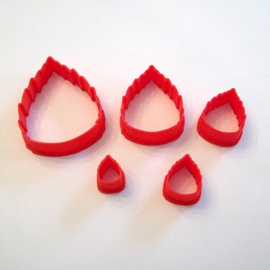 May include: Set of five red plastic cookie cutters shaped like flames. The cutters are different sizes.