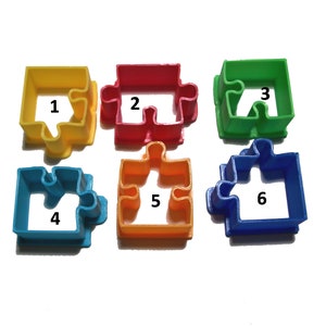 Puede incluir: Seis cortadores de galletas con forma de rompecabezas de colores. Los cortadores son de color amarillo, rojo, verde, azul, naranja y azul oscuro. Cada cortador tiene un número blanco del 1 al 6. Los cortadores son de plástico.