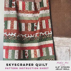 May include: A Skyscraper Quilt pattern instruction sheet. The quilt features a patchwork design with alternating horizontal stripes of red, green, and white fabrics. The fabrics are decorated with floral, candy cane, and other festive patterns. The quilt is made with 2.5" strips.