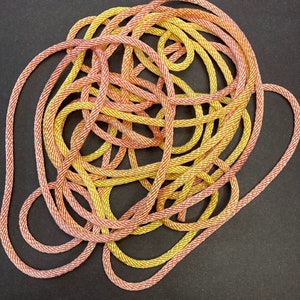 May include: A tangled ball of yellow and pink rope. The rope is made of a soft, textured material and is perfect for crafting or decorating.