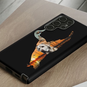 May include: A black phone case with a silhouette of a dog and a duck in a sunset landscape. The phone case has a camera bump with three lenses.