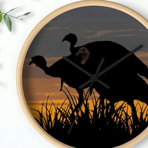 May include: A clock with a silhouette of three turkeys against a sunset background. The clock hands are black and the clock face is a light brown wood.