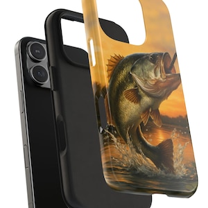 May include: A phone case featuring a leaping bass fish illustration against a sunset backdrop. The case is a combination of black and gold, with the fish in shades of green, brown, and white. The design is detailed, showing water splashes and the fish's open mouth.