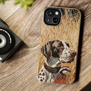 May include: A phone case with a brown and white dog and a quail in a field of tall grass. The dog is looking to the right and the quail is looking to the left. The phone case has a camera lens cutout in the upper left corner.
