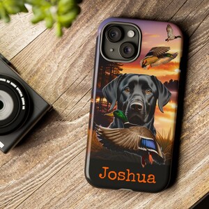 May include: Black Labrador Retriever phone case with a sunset background and ducks flying. The case has the name "Joshua" printed on the bottom.