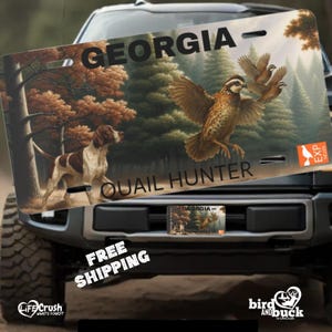 May include: A Georgia license plate featuring a hunting scene with a dog and quail. The plate reads "GEORGIA" at the top and "QUAIL HUNTER" at the bottom. The background depicts a forest with trees and a bird in flight.