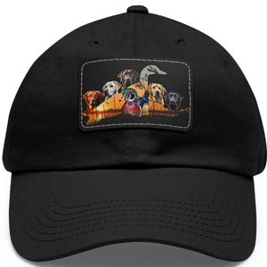 May include: Black baseball cap with a patch featuring a group of dogs and a duck in a hunting scene. The patch has a brown, orange, and green background with the text "If you're hunting, we're hunting."