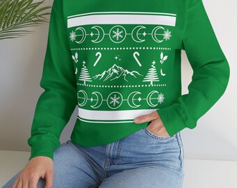 Puede incluir: Una sudadera verde con un diseño blanco de temática invernal que presenta una montaña, árboles, bastones de caramelo, copos de nieve y lunas crecientes.