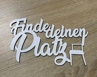 May include: White wooden sign with the text "Find your Platz" in a cursive font. A small chair silhouette is next to the text.