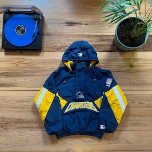 Könnte beinhalten: Marineblaue und gelbe Chargers Anorakjacke mit Kapuze. Die Jacke hat den Teamnamen auf der Brust und das NFL-Logo auf dem Ärmel. Auf der Kapuze befindet sich ein Starter-Logo.