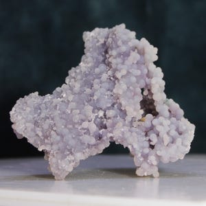 May include: A purple agate geode with a unique, intricate, and bubbly texture. The geode is a natural formation with a hollow center lined with crystals.