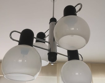 Könnte beinhalten: Eine Deckenleuchte aus Chrom und Schwarz mit fünf weißen, kugelförmigen Schirmen. Die Leuchte hat ein modernes Design mit einer zentralen Chromstange und Armen, die sich zu den Schirmen erstrecken.