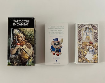 May include: Three tarot card boxes with colourful illustrations. The box on the left has a black background with white text that reads "Tarocchi Incantati". The box in the middle has a white background with black text that reads "I Tarocchi Incantati The Enchanted Tarot Tarot Enchante Elfenzauber Tarot El Tarot Encantado Art by Cincuenta Giandomeni Lo Scarabed Tarocchi D'Arte". The box on the right has a white background with a colourful illustration of a fairy tale scene.