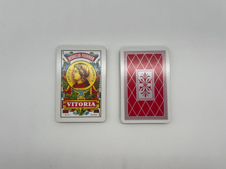 May include: Two playing cards, one with a portrait of a person and the text "Heraclio Fournier" and "Vitoria", the other with a red diamond pattern.