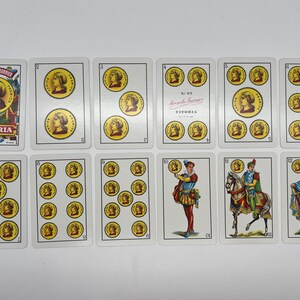 May include: A set of 11 playing cards featuring illustrations of people, animals, and coins. The cards are white with red and black text. The text on the cards includes "Victoria" and "N.&ordm; 87."