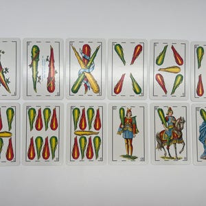 May include: A set of 12 playing cards featuring a variety of designs, including swords, cups, and coins. The cards are in a traditional Spanish style with colorful illustrations and ornate borders.