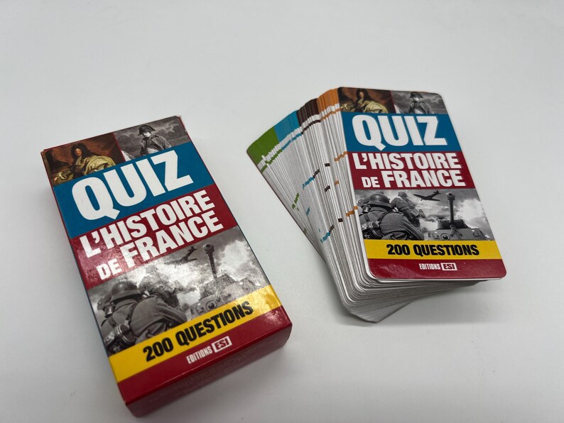 Peut inclure: Une bo&icirc;te rouge et blanche avec le texte "QUIZ L'HISTOIRE DE FRANCE 200 QUESTIONS" sur le devant. La bo&icirc;te contient un jeu de cartes avec le m&ecirc;me texte sur le devant. Les cartes sont blanches avec du texte noir et des images.