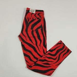 Könnte beinhalten: Rote und schwarze Jeans mit Zebra-Muster. Die Jeans haben eine hohe Taille und ein gerades Bein.