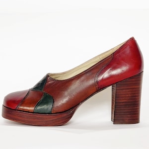 May include: A pair of brown leather platform shoes with a chunky heel. The shoes have a patchwork design with red, green, and brown leather pieces.