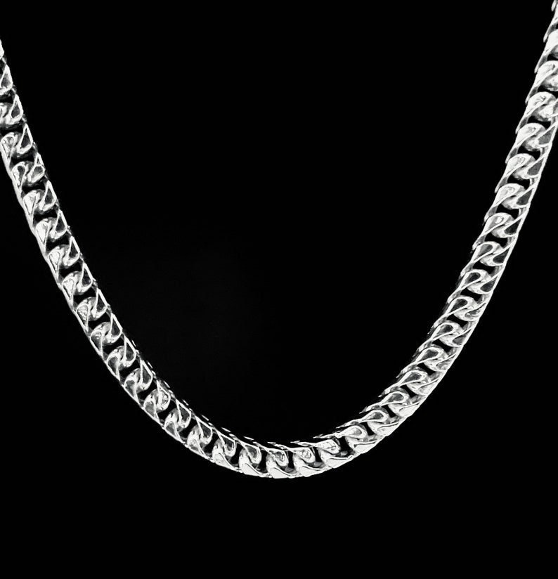 May include: A silver chain necklace with a curb link design.