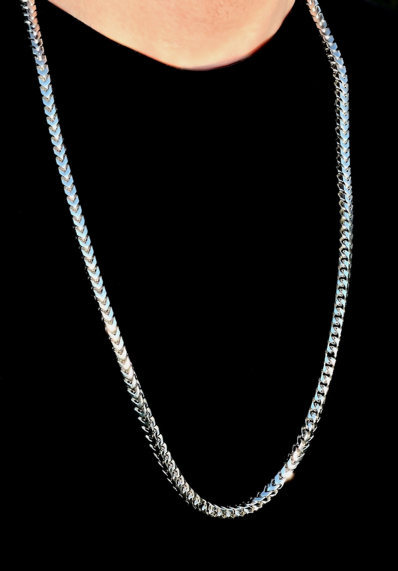 May include: A silver chain necklace with a herringbone pattern.