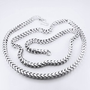 May include: A silver chain necklace with a box chain design. The chain is made of small, interlocking links that form a box shape.