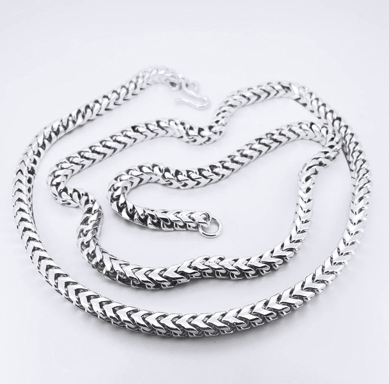 May include: A silver chain necklace with a box chain design. The chain is made of small, interlocking links that form a box shape.