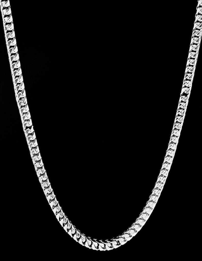 May include: A silver chain necklace with a curb link style. The chain is made of metal and has a shiny finish.