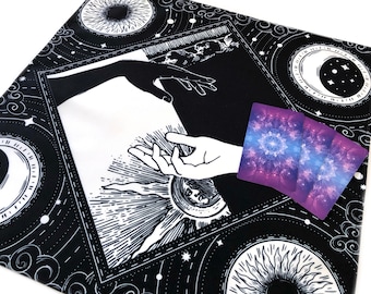 Peut inclure: Tapisserie noire et blanche avec un motif céleste représentant un soleil, une lune et des étoiles. La tapisserie a une bordure blanche et un fond noir. Il y a trois cartes de tarot sur la tapisserie.