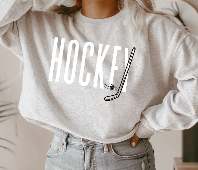 May include: A gray sweatshirt with the word "HOCKEY" and a hockey stick and puck graphic printed on the front.