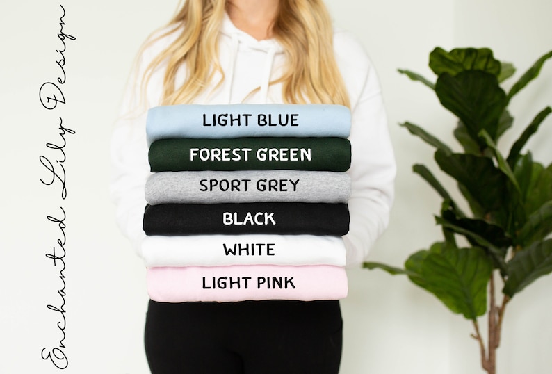 May include: A stack of six sweatshirts in different colors: light blue, forest green, sport grey, black, white, and light pink. The sweatshirts are folded and stacked on top of each other.