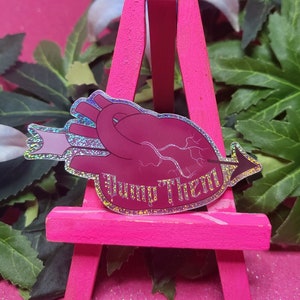 Op de afbeelding: Een holografische sticker met een roze hart dat door een pijl wordt doorboord en de tekst "Jump Them". De sticker zit op een roze ezel.