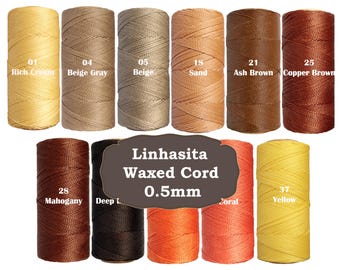 May include: A collection of spools of Linhasita waxed cord in various colors, including cream, beige, sand, brown, and yellow. The spools are labeled with color names and numbers, and the cord is 0.5mm thick.