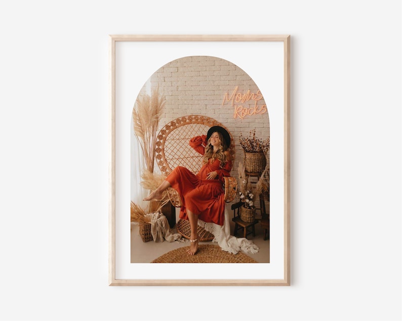 May include: A woman in a red dress sits in a wicker chair with a neon sign that says "Momma Rocks" in the background.