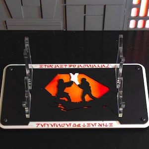 May include: A black and white display stand with a red and orange silhouette of two figures fighting. The stand has the text "ETNIK METPO MAVMAV" and "7VVYVVVOV 0K LEVT NILE" on it.