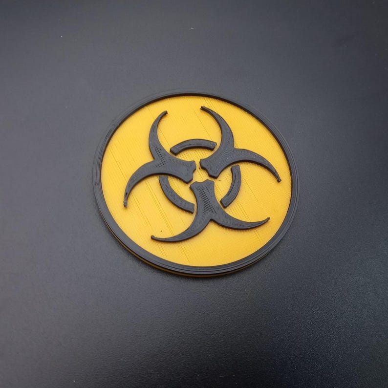 May include: A yellow circle with a black biohazard symbol in the centre. The symbol is a stylised three-pronged shape.