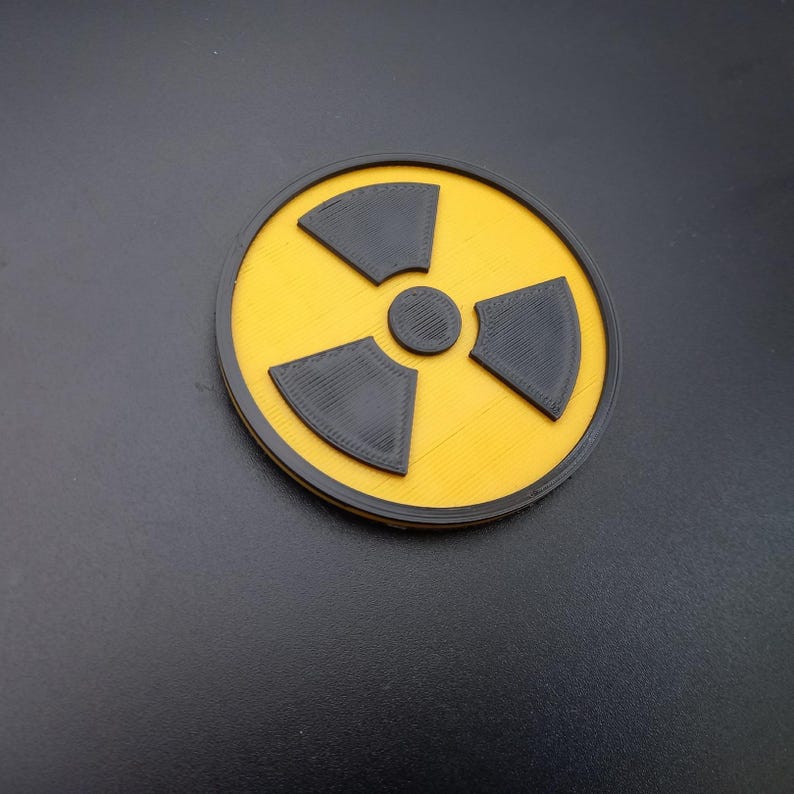May include: A yellow and black radiation warning symbol. The symbol is a circle with a black tri-lobed symbol inside.
