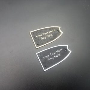 May include: Two black guitar pick-shaped plaques with a silver border. The plaques have the text "Your Text Here Any Font" engraved on them.
