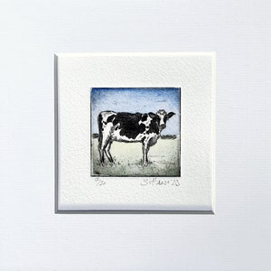 Könnte beinhalten: Schwarz-weiß-Illustration einer Kuh auf einer Weide mit blauem Himmel. Das Bild ist signiert mit "S. Hare '23" und nummeriert "7/50".
