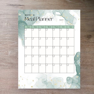 May include: A printable monthly meal planner with a green and gold watercolor background. The planner has a grid with boxes for each day of the week, labeled Sun, Mon, Tues, Wed, Thurs, Fri, Sat. The text "MONTHLY - Meal Planner" is at the top of the page.
