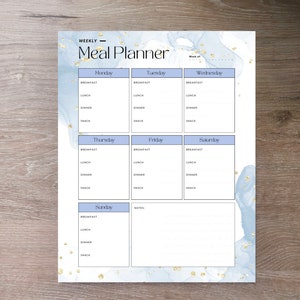 May include: A weekly meal planner with a blue and white watercolor background and gold glitter accents. The planner is divided into seven sections for each day of the week, with spaces for breakfast, lunch, dinner, and snack.